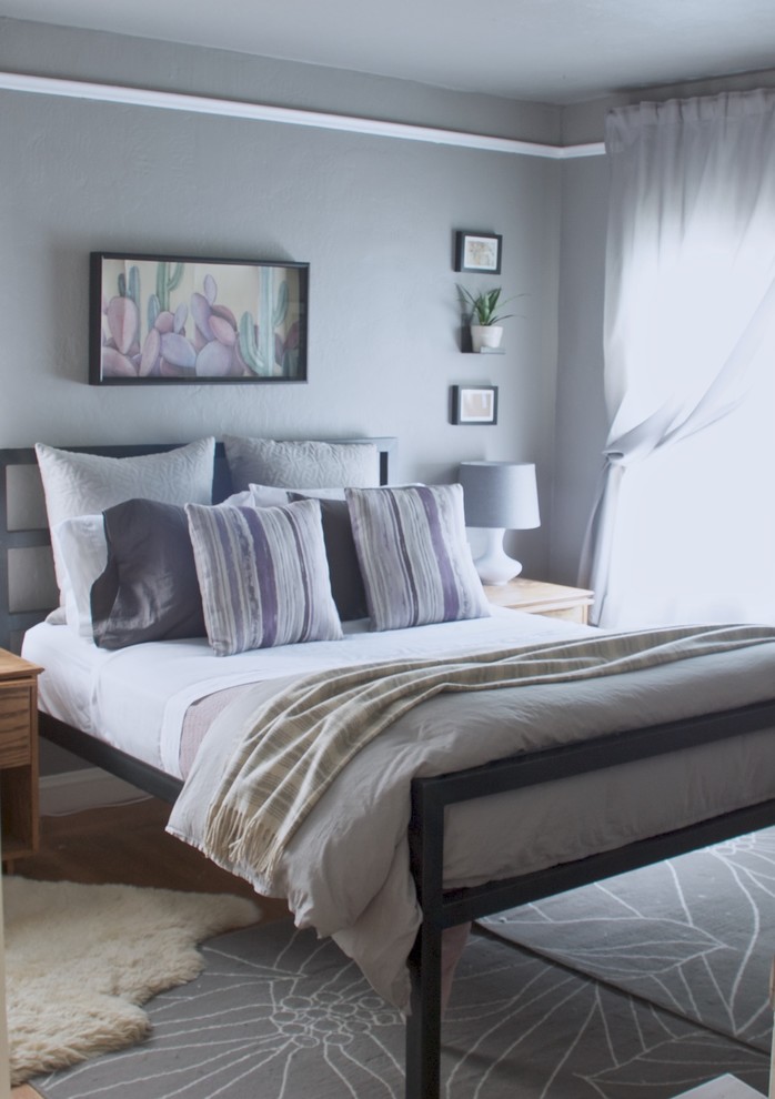 Modelo de habitación de invitados de estilo americano de tamaño medio sin chimenea con paredes grises y suelo de madera clara