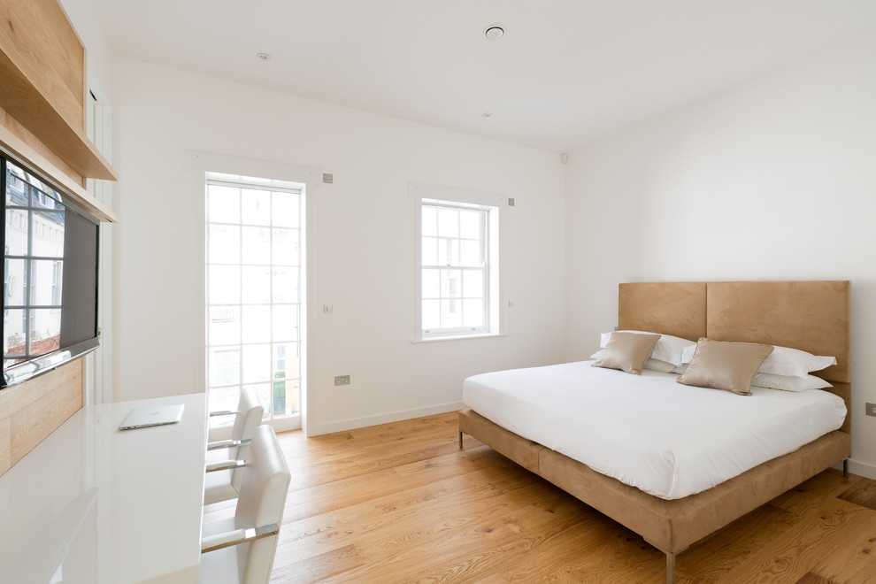 Imagen de habitación de invitados actual de tamaño medio con paredes blancas, suelo de madera en tonos medios y suelo marrón