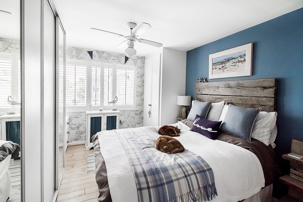 На фото: хозяйская спальня среднего размера в морском стиле с синими стенами, светлым паркетным полом и коричневым полом без камина с