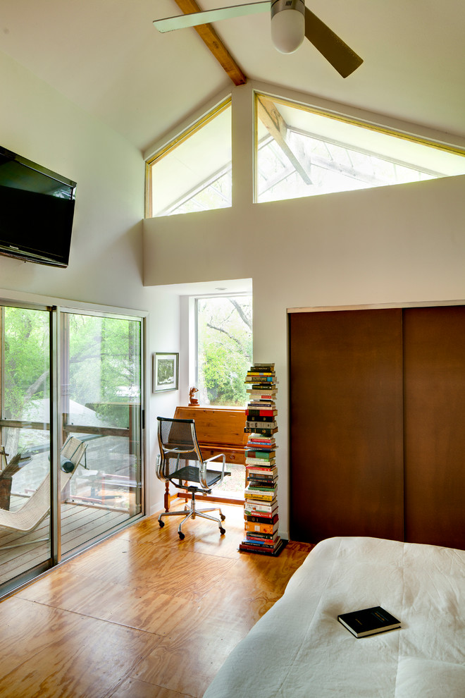 Immagine di una camera da letto contemporanea con pareti bianche e pavimento in compensato