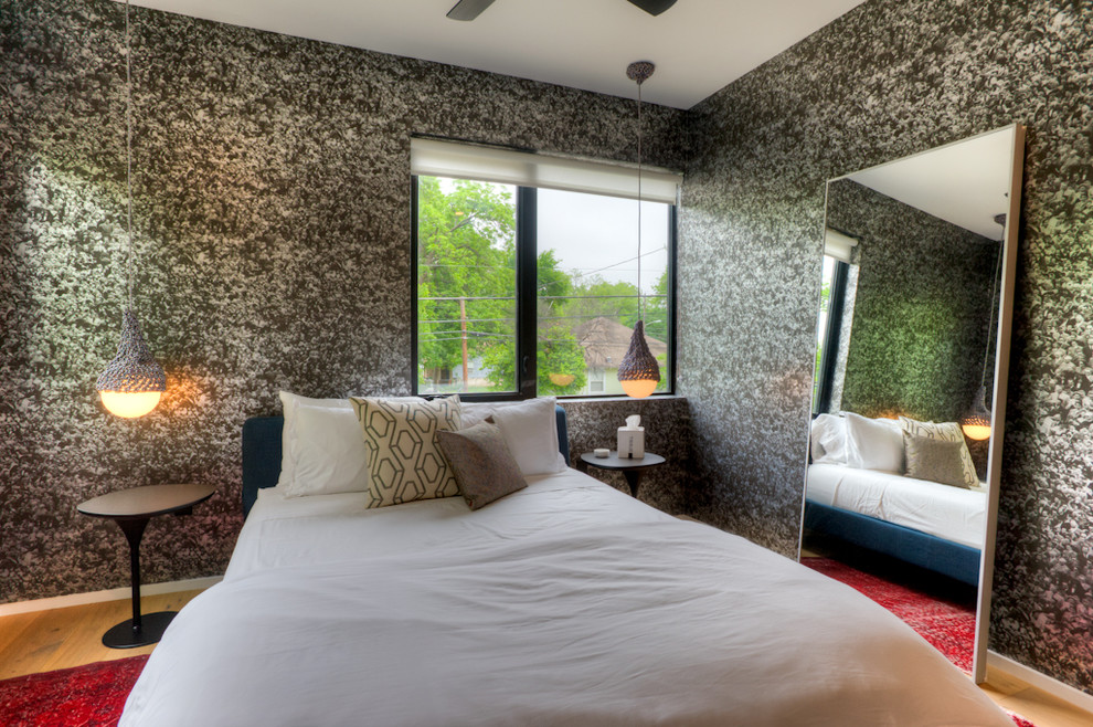 Diseño de habitación de invitados actual de tamaño medio sin chimenea con paredes negras y suelo de madera clara