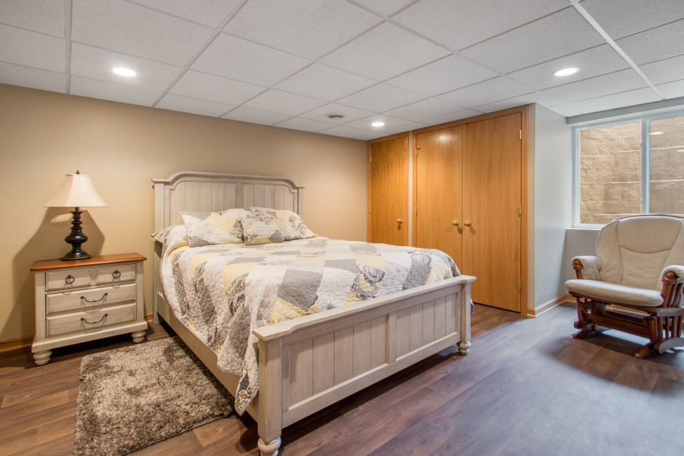 Modelo de habitación de invitados clásica de tamaño medio con paredes beige, suelo vinílico y suelo marrón