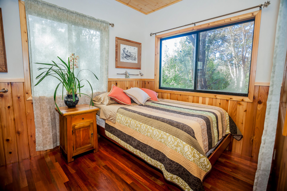 Kleines Uriges Gästezimmer mit weißer Wandfarbe und braunem Holzboden in Hawaii
