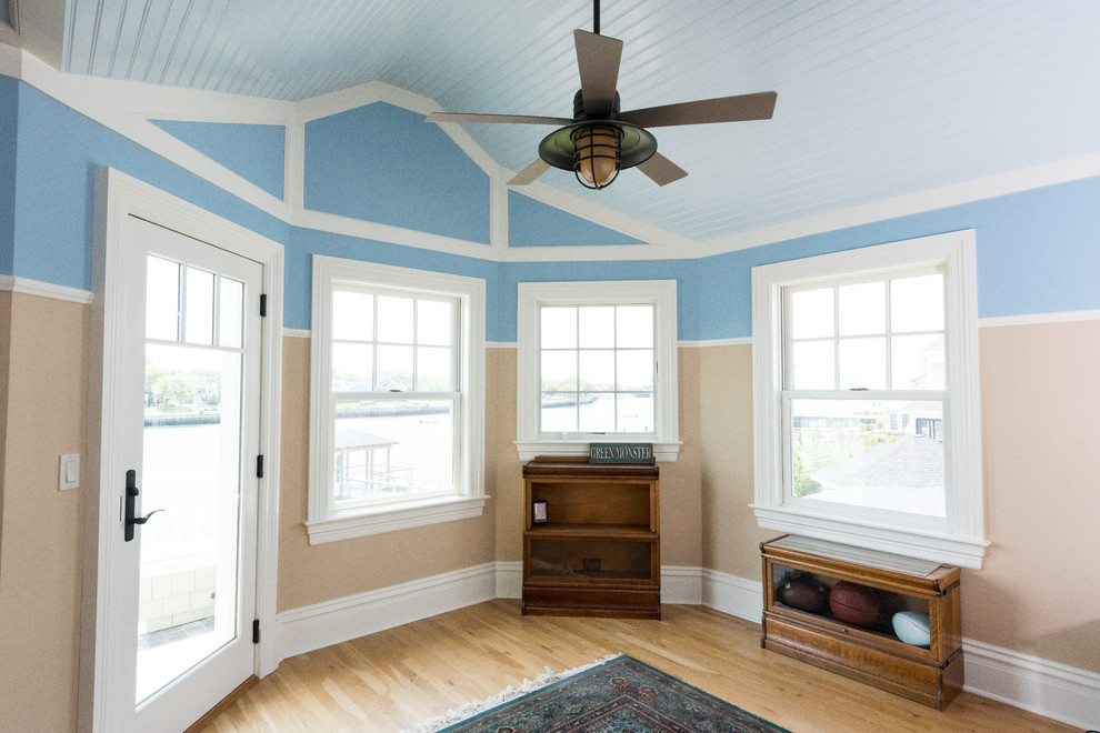 Ejemplo de habitación de invitados costera de tamaño medio sin chimenea con paredes azules y suelo de madera en tonos medios