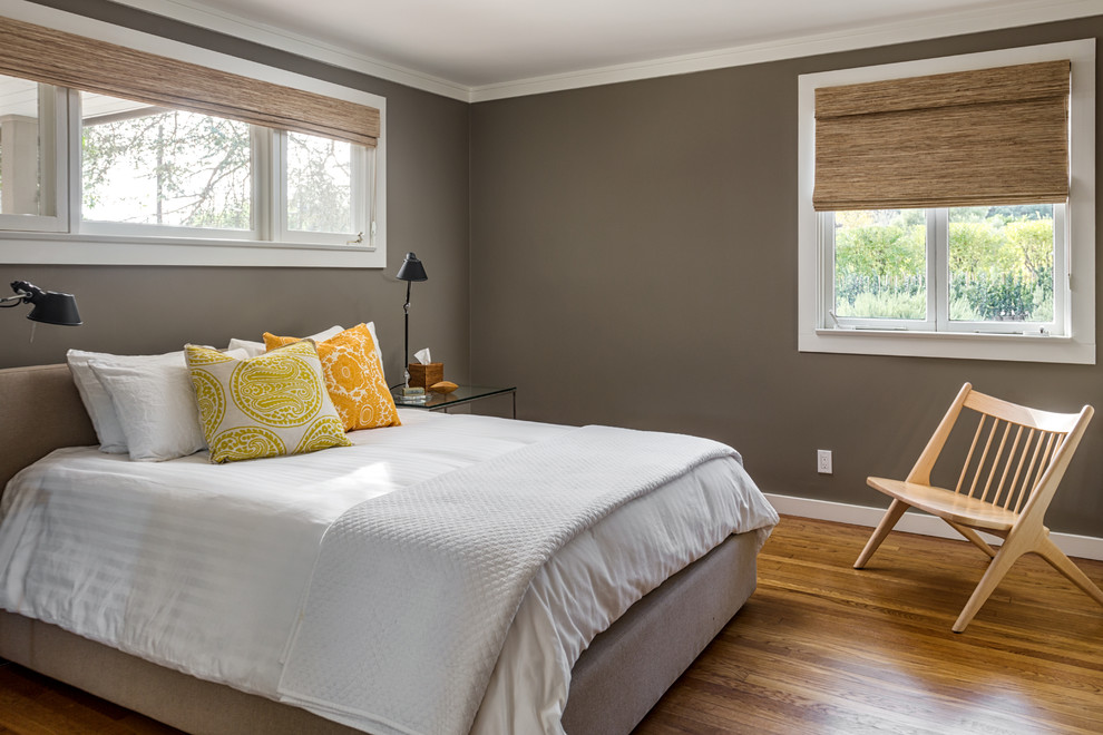 Cette photo montre une chambre d'amis moderne de taille moyenne avec un mur gris, un sol en bois brun et aucune cheminée.