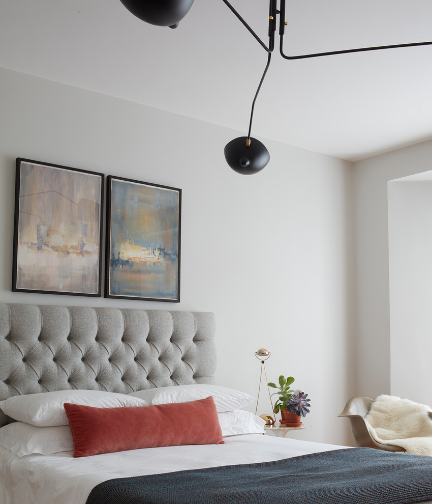 Mid-sized transitional guest brown floor and medium tone wood floor bedroom photo in Devon with gray walls, a standard fireplace and a plaster fireplace