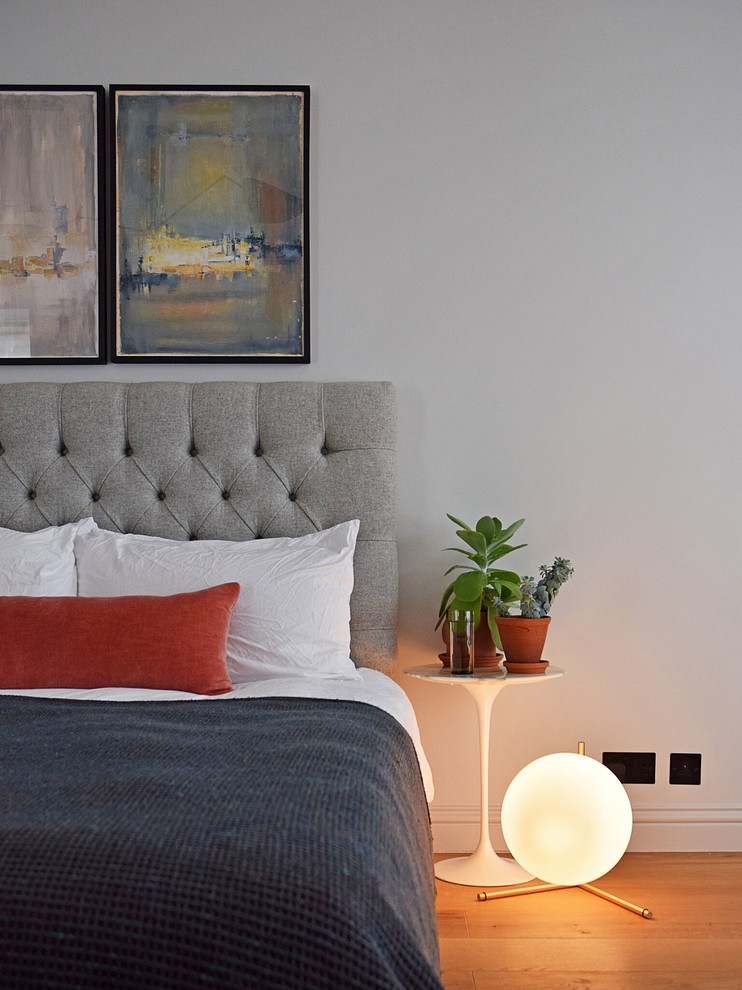 Пример оригинального дизайна: гостевая спальня среднего размера, (комната для гостей): освещение в стиле неоклассика (современная классика) с серыми стенами, паркетным полом среднего тона, стандартным камином, фасадом камина из штукатурки и коричневым полом