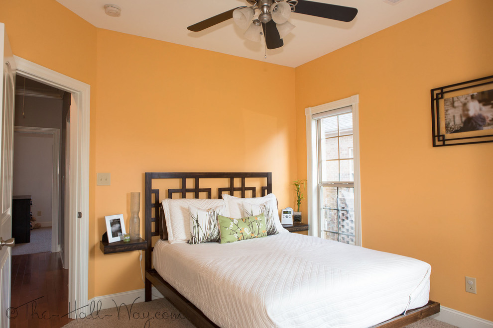 Inredning av ett klassiskt litet gästrum, med orange väggar och heltäckningsmatta