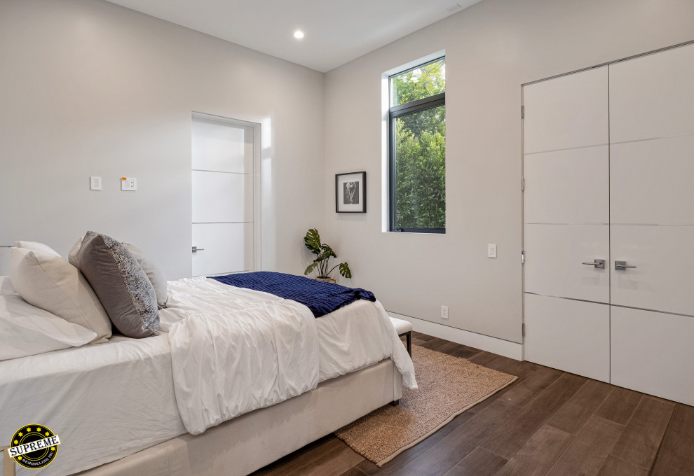 Immagine di una camera degli ospiti minimalista di medie dimensioni con pareti bianche, pavimento in legno massello medio e pavimento marrone