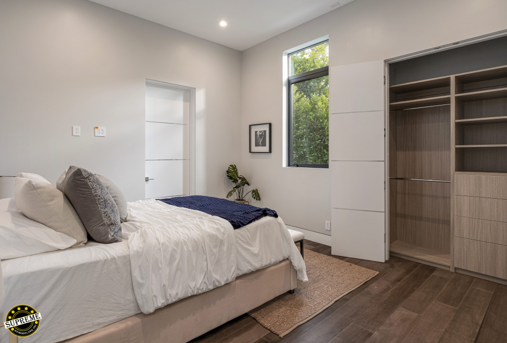 Exemple d'une chambre d'amis moderne de taille moyenne avec un mur blanc, un sol en bois brun et un sol marron.