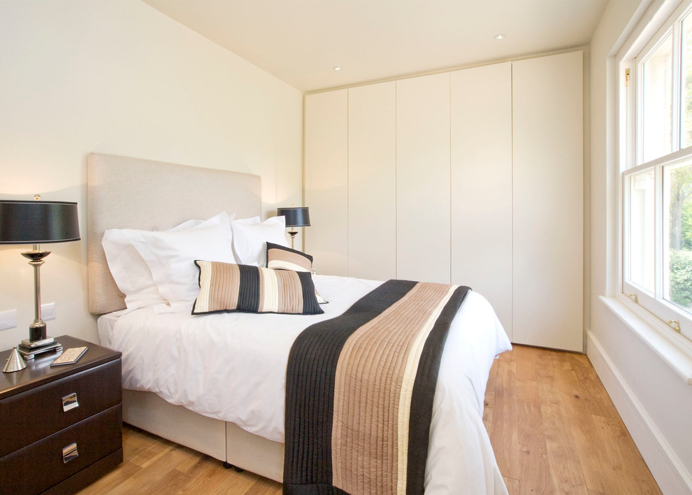 Diseño de habitación de invitados contemporánea pequeña con paredes beige y suelo de madera clara