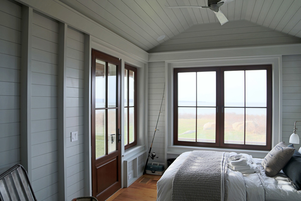 Imagen de habitación de invitados costera grande con paredes blancas y suelo de madera en tonos medios