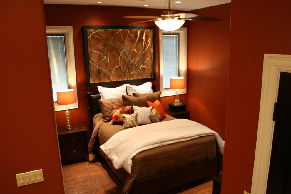 Ispirazione per una piccola camera matrimoniale design con pareti arancioni e pavimento in legno massello medio