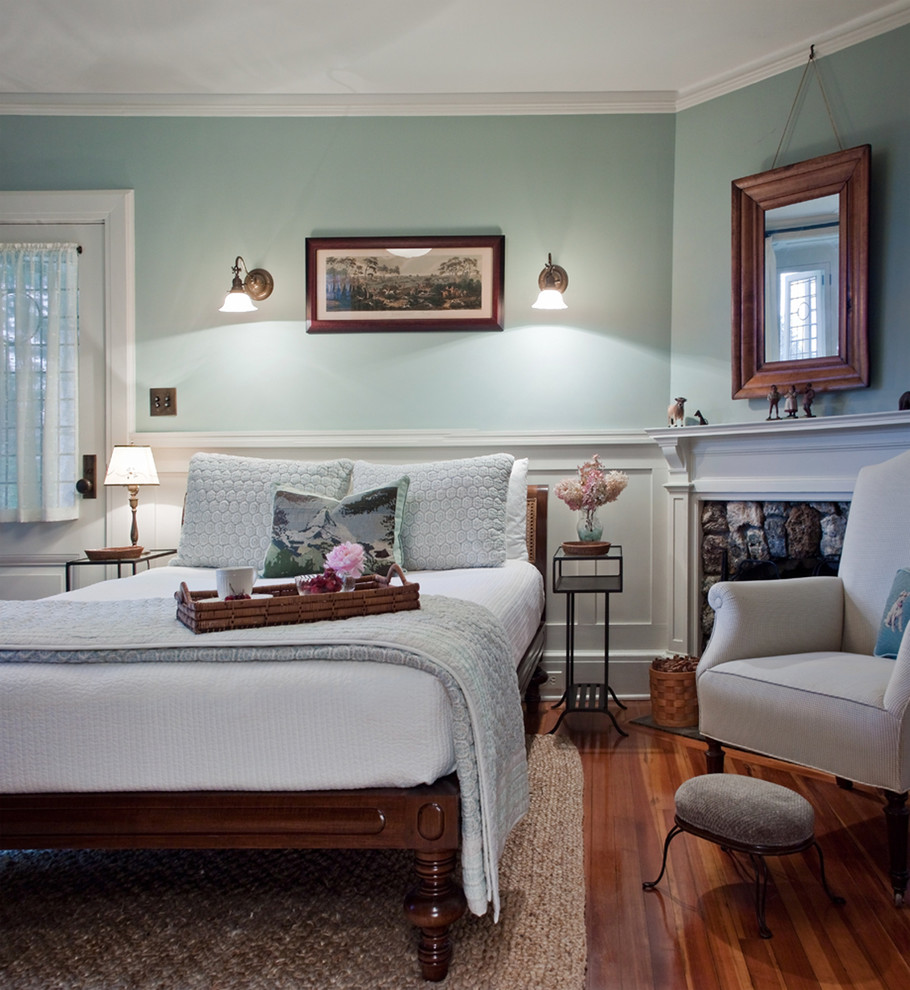 На фото: гостевая спальня (комната для гостей) в стиле кантри с синими стенами, паркетным полом среднего тона и угловым камином с
