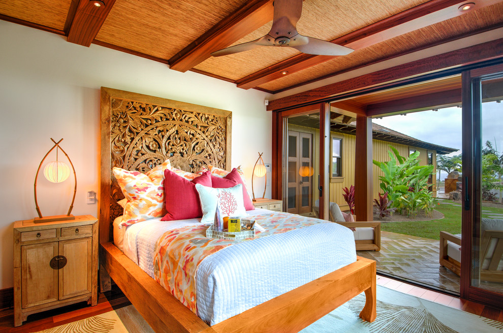 Immagine di una camera degli ospiti tropicale di medie dimensioni con pareti bianche, pavimento in legno massello medio, pavimento marrone e nessun camino