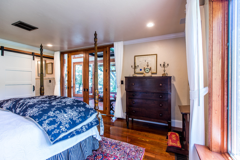 Ejemplo de habitación de invitados tradicional de tamaño medio sin chimenea con paredes amarillas, suelo de madera en tonos medios y suelo rojo
