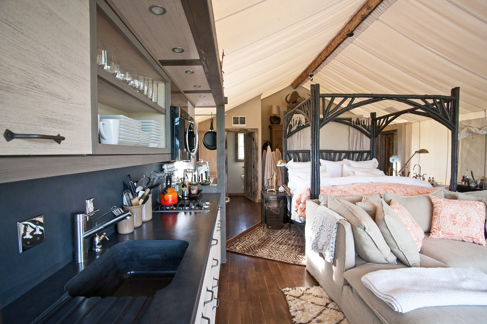 Modelo de dormitorio rural sin chimenea con paredes beige y suelo de madera oscura
