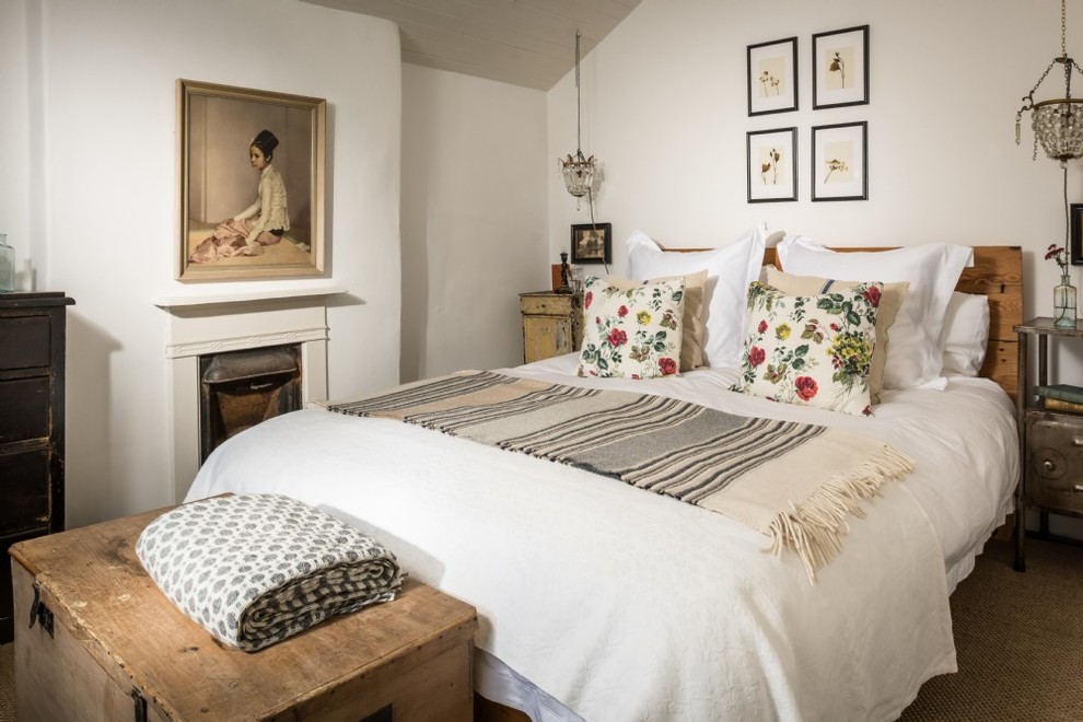 Mittelgroßes Country Hauptschlafzimmer mit weißer Wandfarbe, Teppichboden, Kamin, verputzter Kaminumrandung und beigem Boden in Cornwall