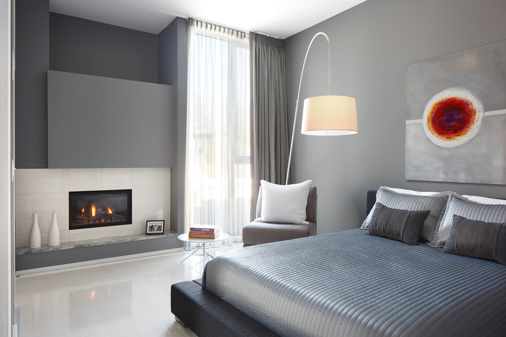 На фото: спальня в современном стиле с серыми стенами, стандартным камином и белым полом с