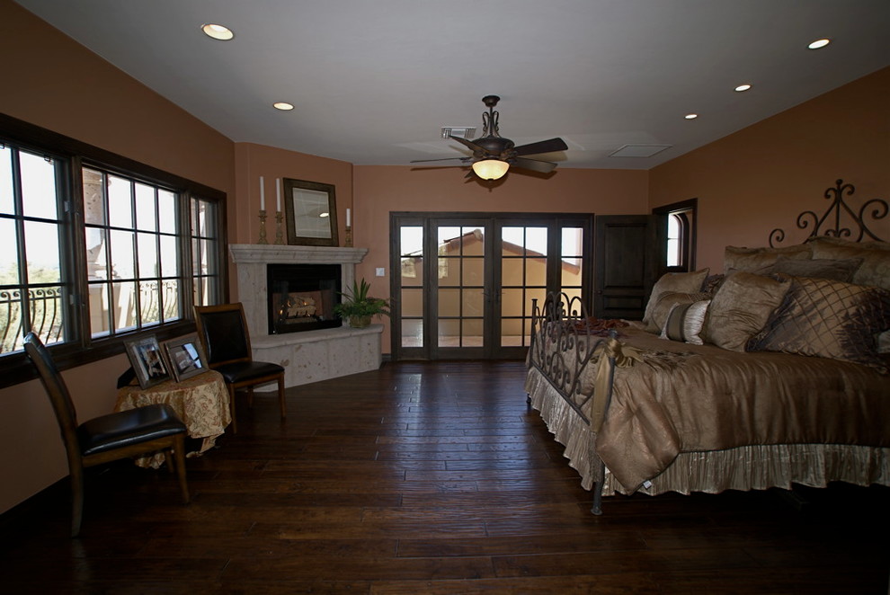 Bild på ett stort vintage sovrum, med orange väggar, mörkt trägolv, en standard öppen spis och en spiselkrans i sten