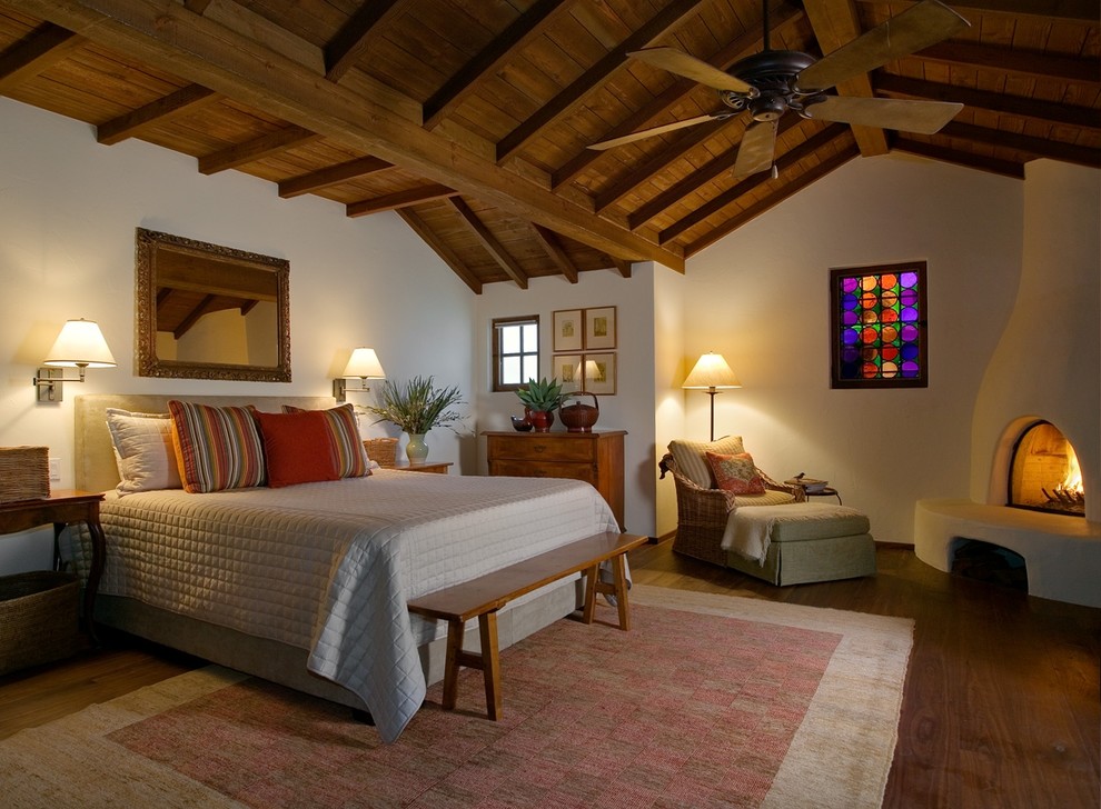 Пример оригинального дизайна: хозяйская спальня среднего размера в стиле фьюжн с белыми стенами, паркетным полом среднего тона, угловым камином и фасадом камина из штукатурки