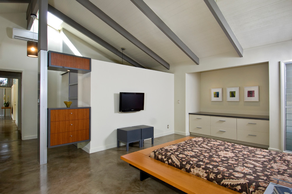 Imagen de dormitorio minimalista con suelo de cemento y paredes blancas