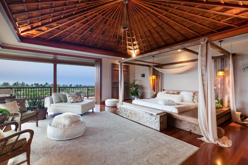 Idee per un'ampia camera matrimoniale tropicale con pavimento in legno massello medio e pareti bianche