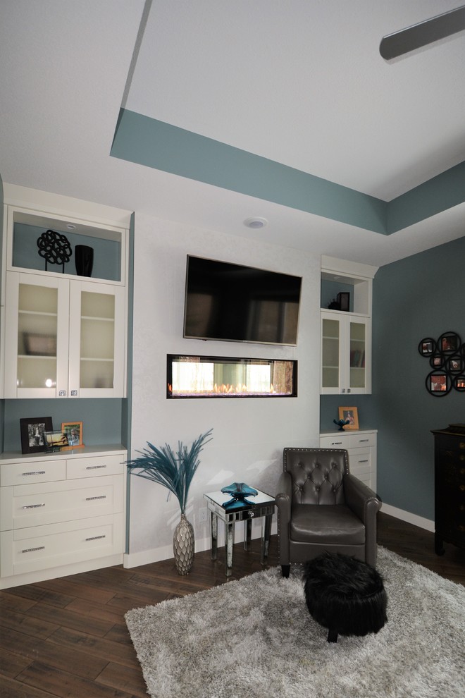 カルガリーにある広いトランジショナルスタイルのおしゃれな主寝室 (青い壁、濃色無垢フローリング、両方向型暖炉、漆喰の暖炉まわり、茶色い床) のレイアウト