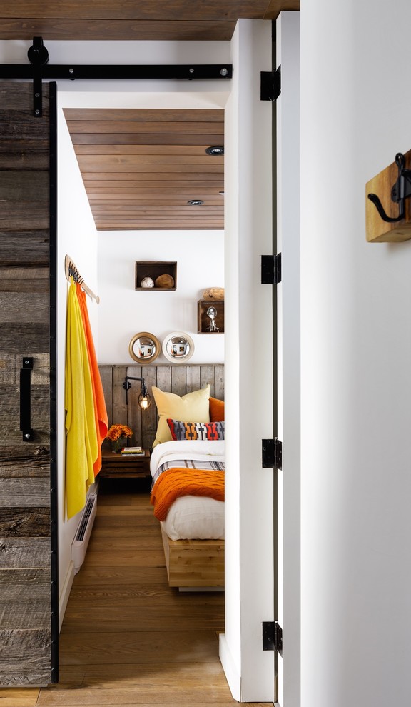 Diseño de habitación de invitados actual pequeña con paredes blancas y suelo de madera en tonos medios
