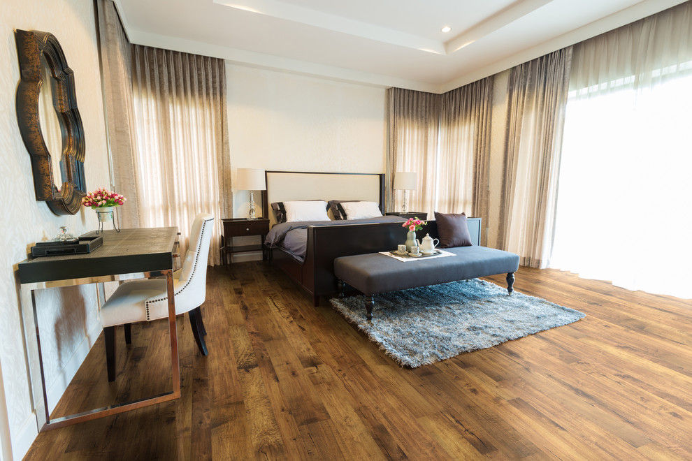 Imagen de dormitorio principal grande sin chimenea con paredes beige, suelo de madera en tonos medios y con escritorio