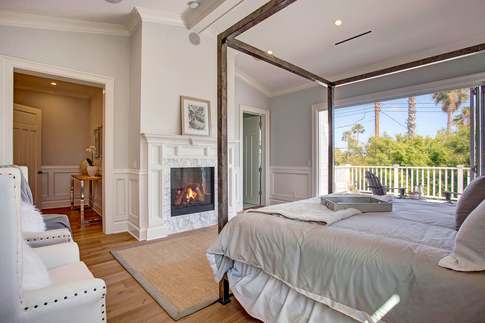 Traditional master bedroom in Los Angeles with light hardwood flooring, a standard fireplace and a stone fireplace surround.