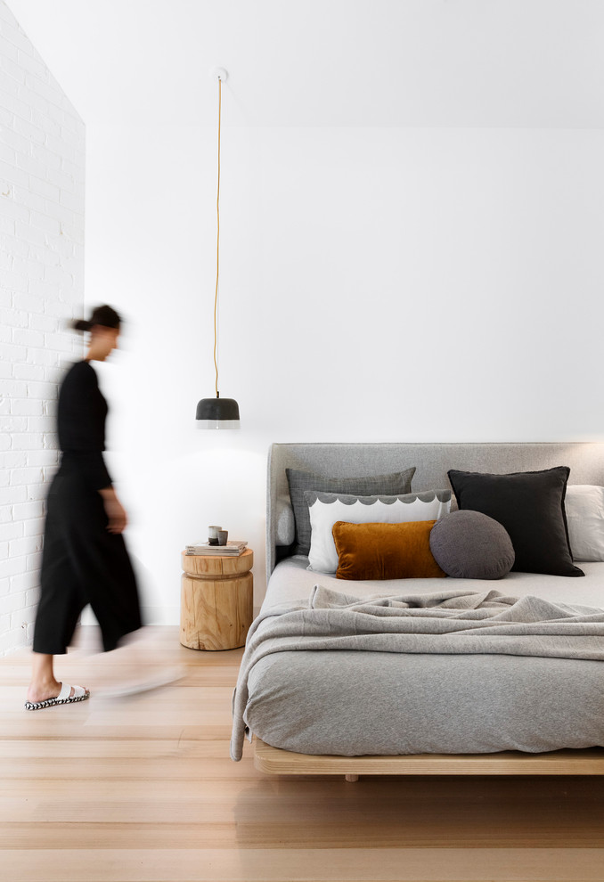 Skandinavisches Schlafzimmer ohne Kamin mit weißer Wandfarbe und hellem Holzboden in Melbourne
