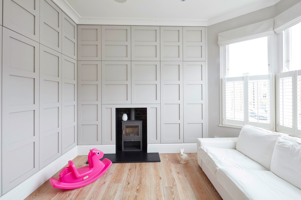 Diseño de dormitorio tradicional grande con paredes grises, suelo de madera en tonos medios y estufa de leña
