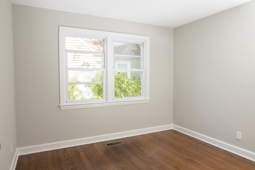 Imagen de habitación de invitados de estilo americano de tamaño medio sin chimenea con paredes grises, suelo de madera en tonos medios y suelo marrón
