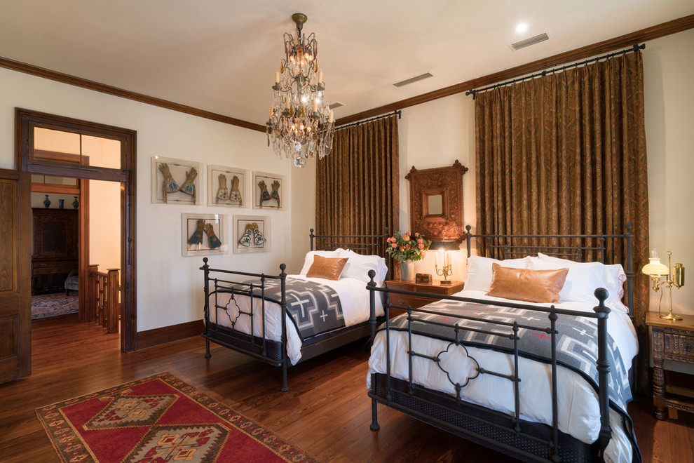 Large elegant guest medium tone wood floor and brown floor bedroom photo in Austin with white walls, a standard fireplace and a metal fireplace
