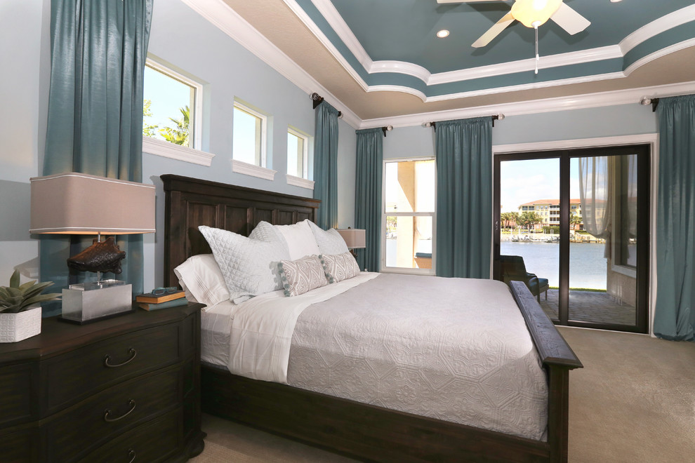 Imagen de dormitorio principal costero grande sin chimenea con paredes azules, moqueta y suelo beige