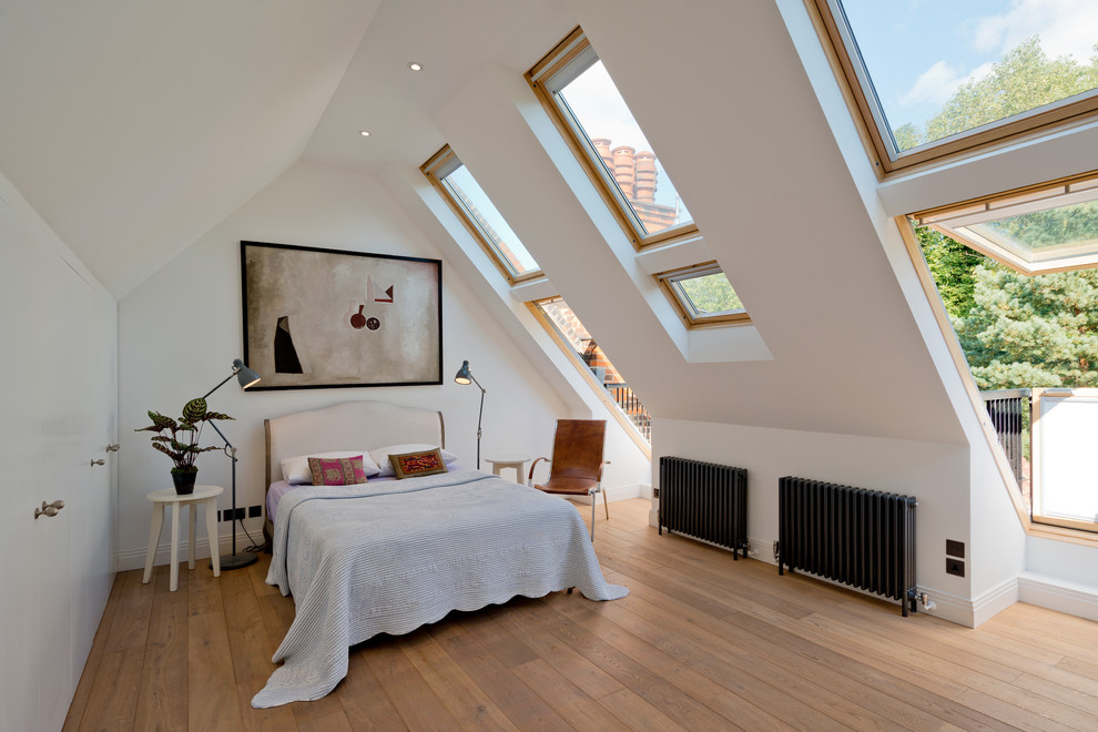 ロンドンにあるコンテンポラリースタイルのおしゃれな寝室 (白い壁、無垢フローリング、暖炉なし、勾配天井)