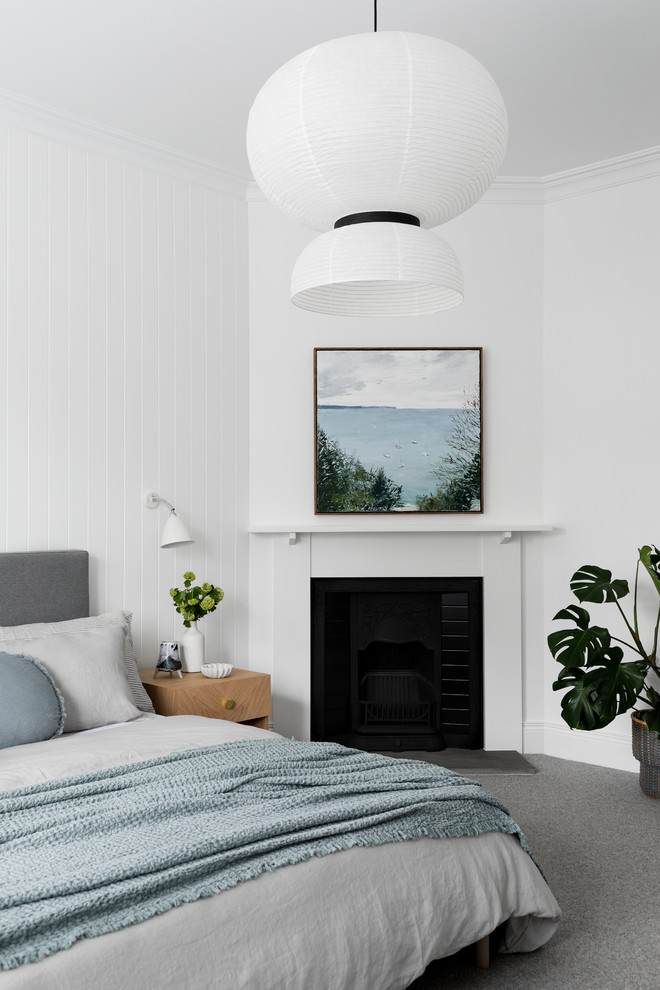 メルボルンにあるコンテンポラリースタイルのおしゃれな主寝室 (白い壁、カーペット敷き、標準型暖炉、木材の暖炉まわり、グレーの床) のインテリア