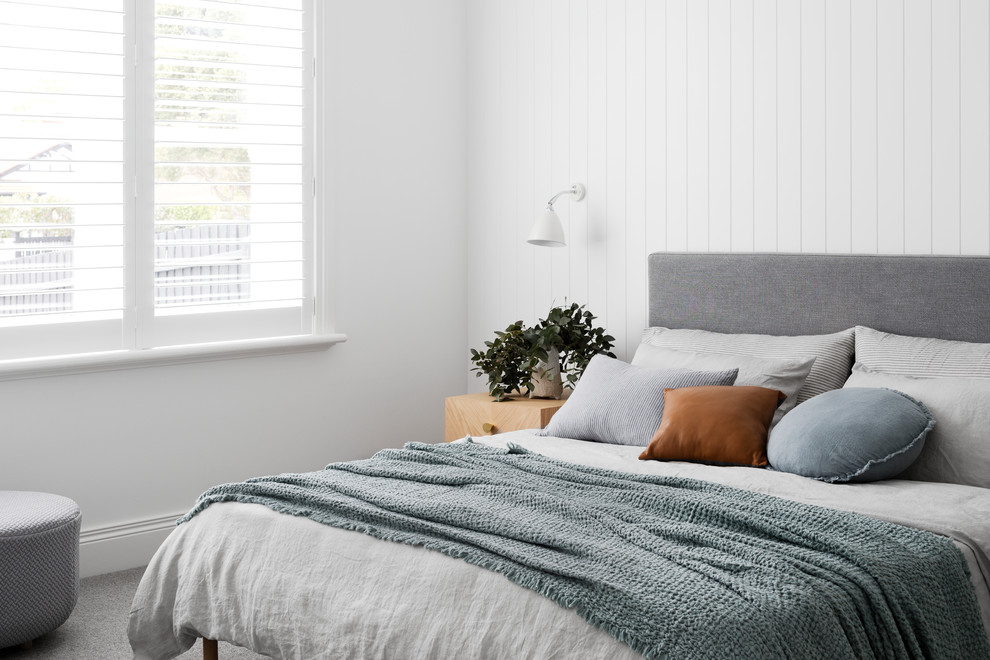 Пример оригинального дизайна: хозяйская спальня в современном стиле с белыми стенами, ковровым покрытием, стандартным камином, фасадом камина из дерева и серым полом