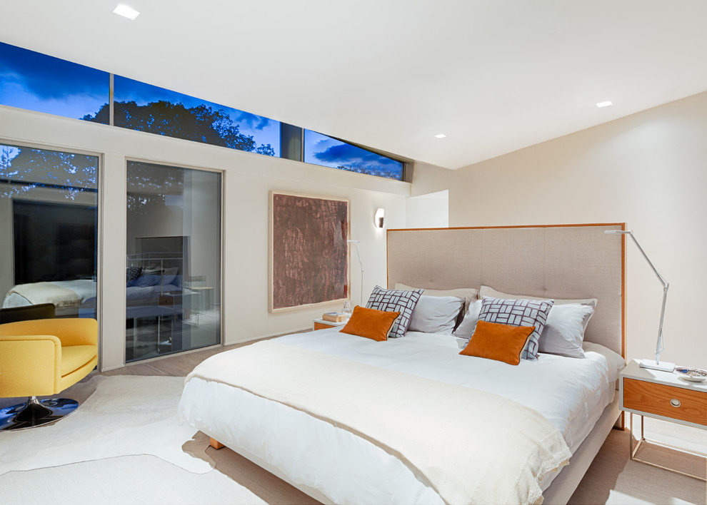 Imagen de dormitorio principal contemporáneo grande con paredes beige, suelo de madera clara y suelo beige