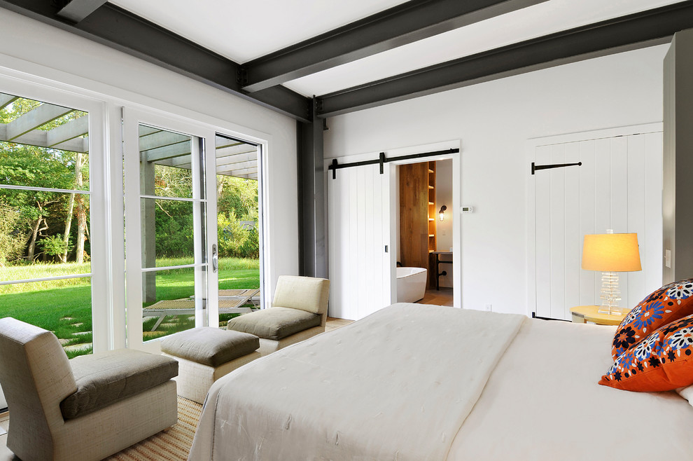 Example of a farmhouse medium tone wood floor and brown floor bedroom design in New York with white walls