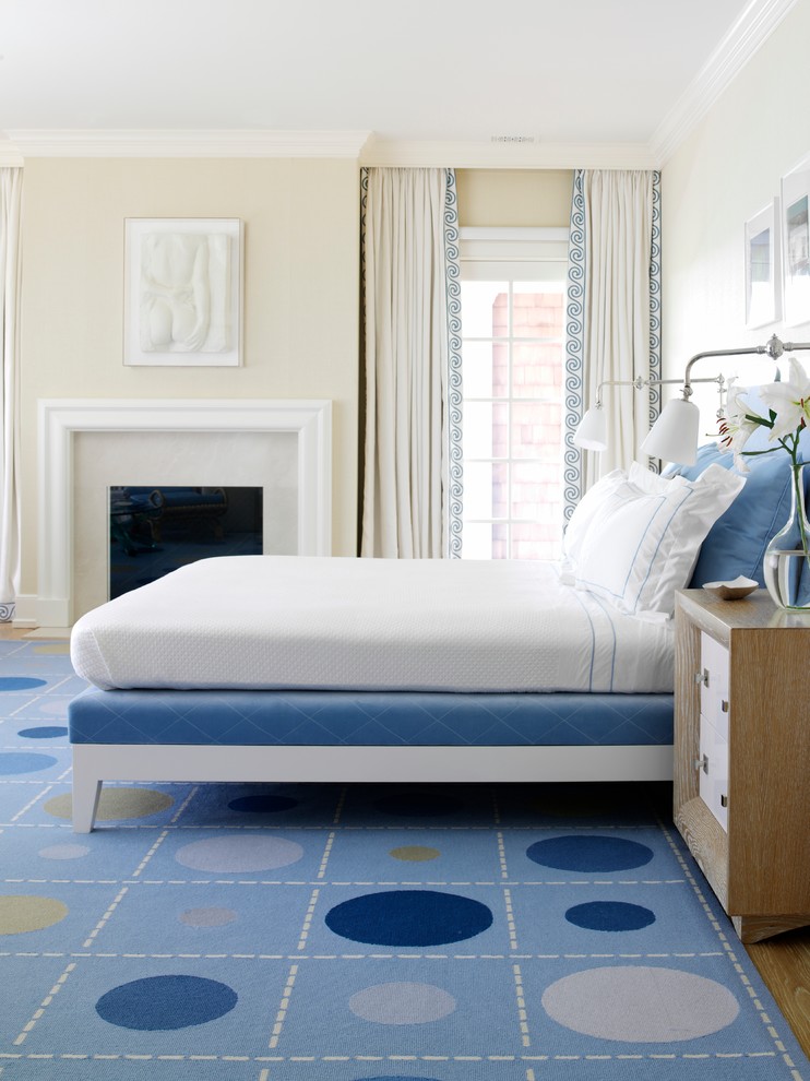 Exempel på ett modernt sovrum, med beige väggar, mellanmörkt trägolv, en standard öppen spis och blått golv