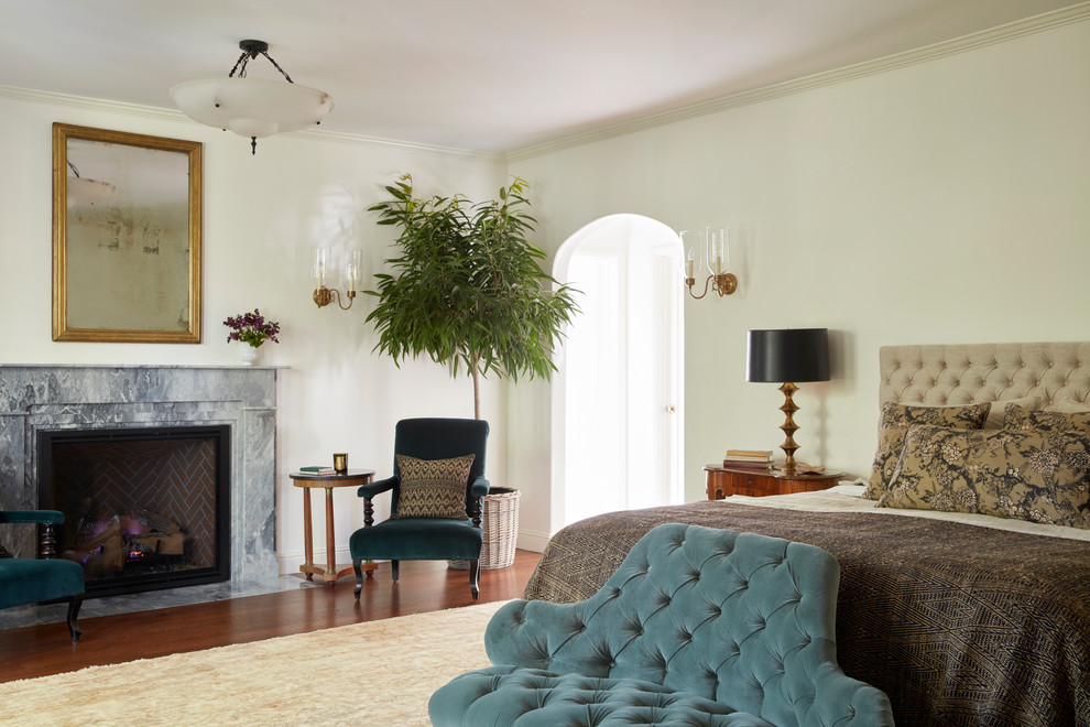 Bedroom - mediterranean master medium tone wood floor and brown floor bedroom idea in Los Angeles with white walls, a standard fireplace and a stone fireplace