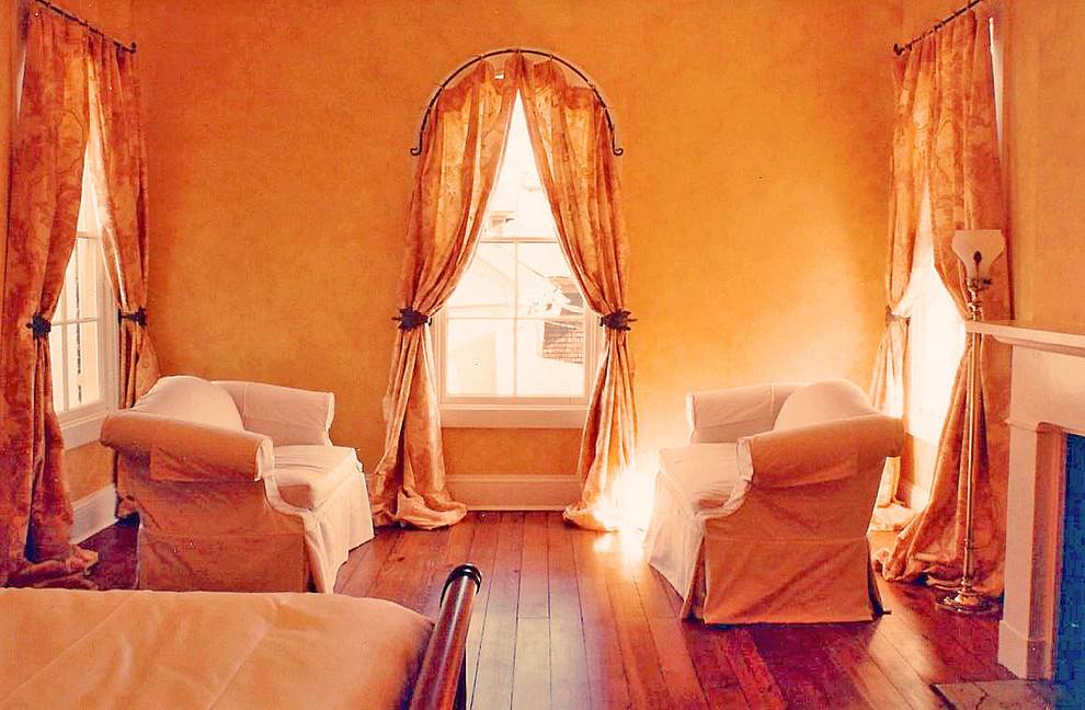 Foto di una grande camera matrimoniale classica con pareti beige, pavimento in legno massello medio, camino classico e cornice del camino in legno