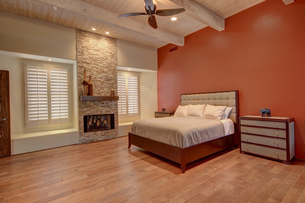 Diseño de dormitorio principal contemporáneo grande con paredes beige, suelo de madera en tonos medios, todas las chimeneas, marco de chimenea de piedra y suelo marrón