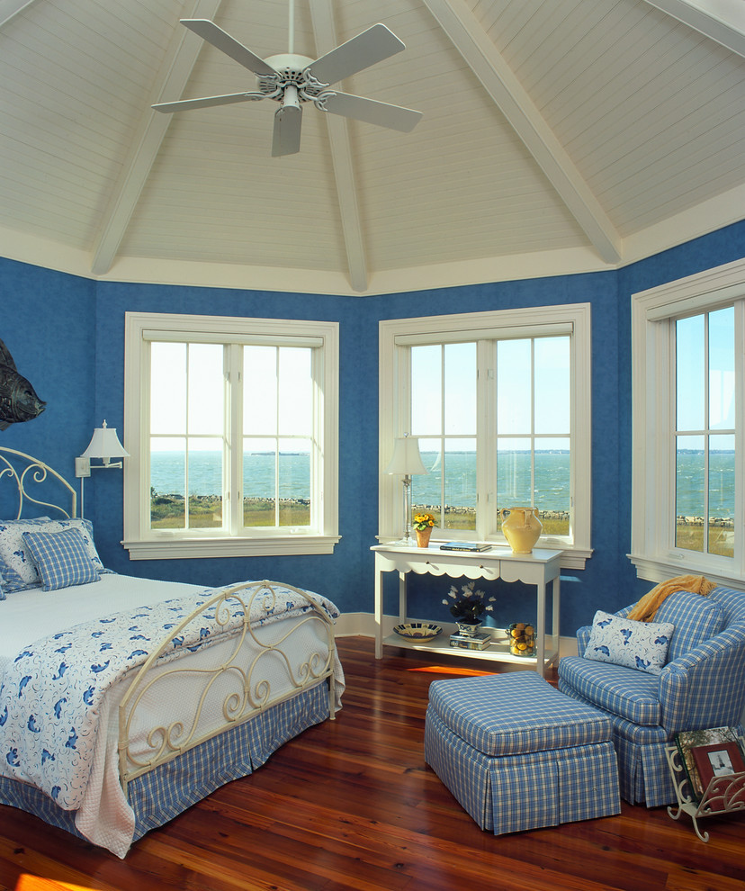 Aménagement d'une chambre bord de mer avec un mur bleu et parquet foncé.