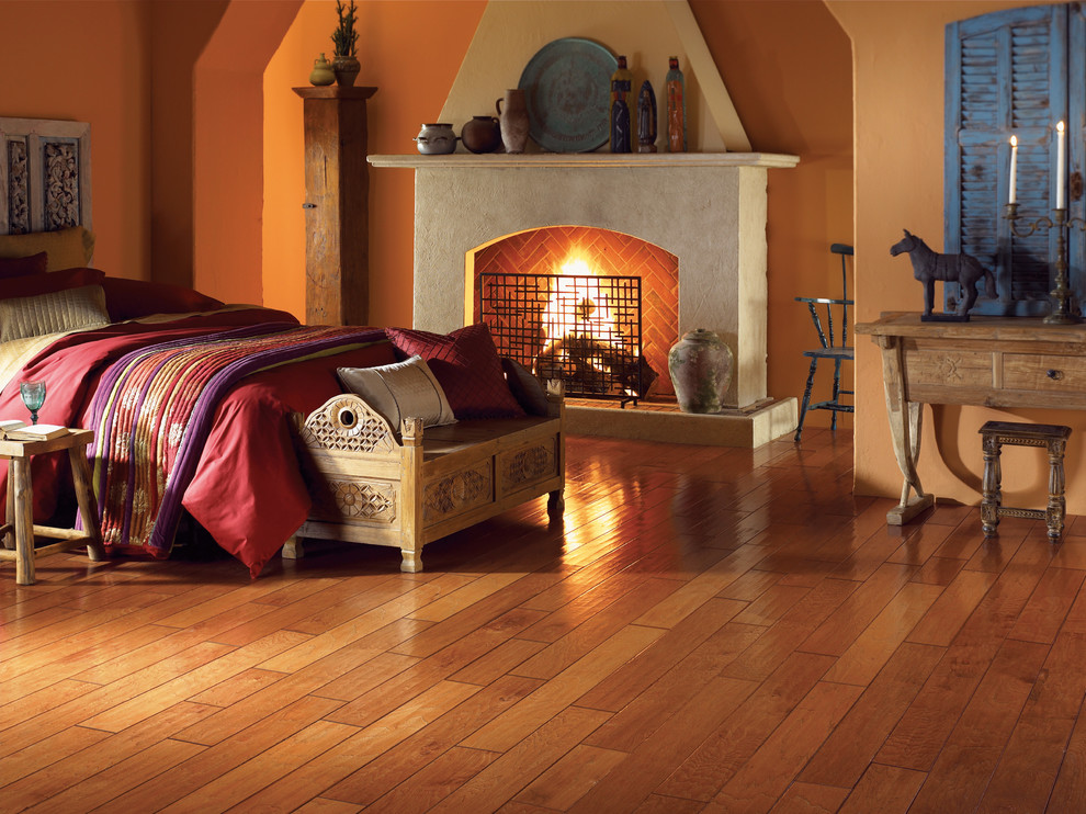 Ejemplo de habitación de invitados de estilo americano grande con paredes beige, suelo de madera clara, todas las chimeneas, marco de chimenea de piedra y suelo marrón