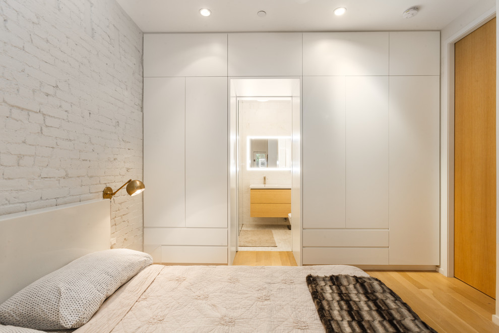 Example of a mid-sized minimalist master light wood floor and beige floor bedroom design in New York with white walls and no fireplace