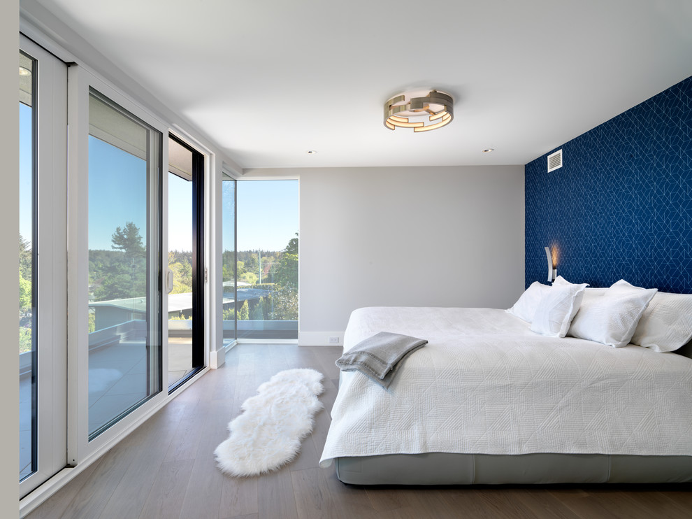 Foto på ett funkis sovrum, med blå väggar och ljust trägolv
