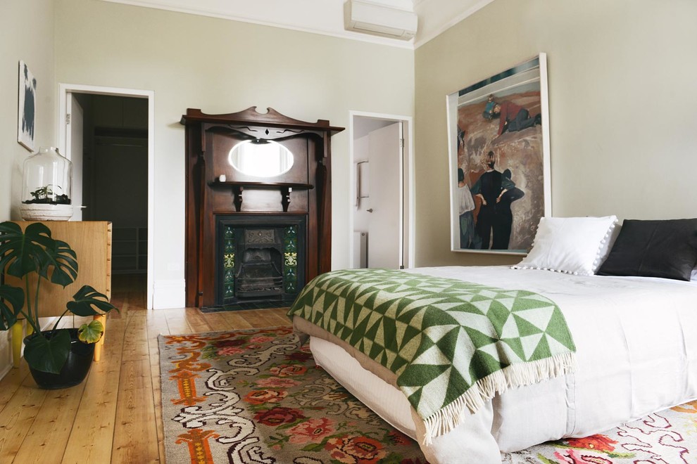 メルボルンにある中くらいなコンテンポラリースタイルのおしゃれな主寝室 (緑の壁、淡色無垢フローリング、標準型暖炉、木材の暖炉まわり) のインテリア